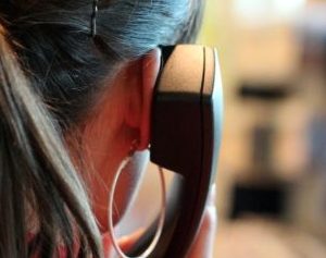 Hinterkopf einer Frau mit Telefonhörer am Ohr
