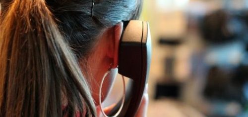 Hinterkopf einer Frau mit Telefonhörer am Ohr