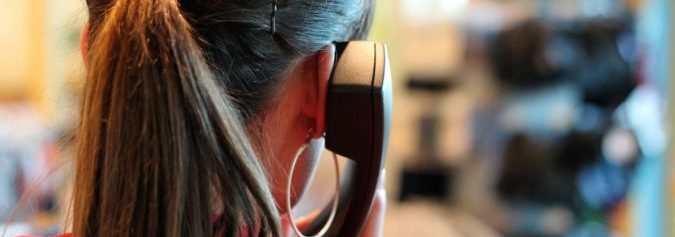 Hinterkopf einer Frau mit Telefonhörer am Ohr