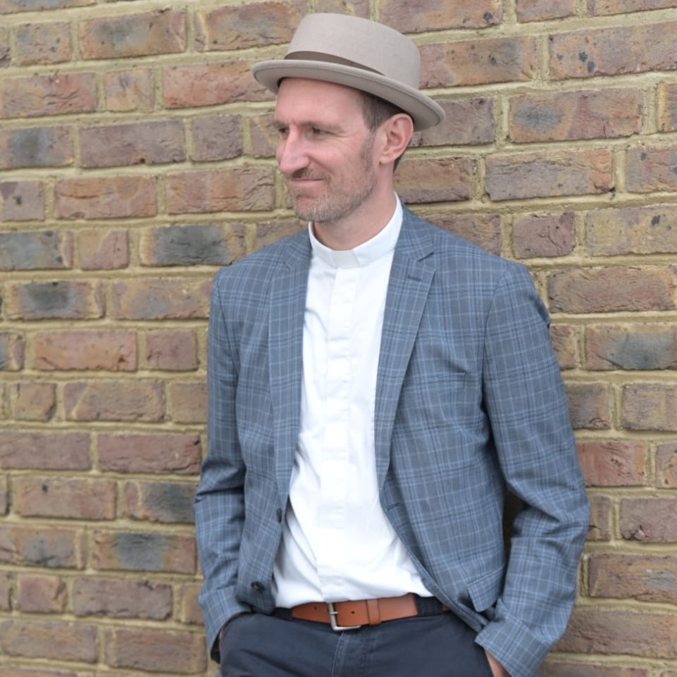 Andreas Hahne mit Hut und Sakko lehnt an einer Wand