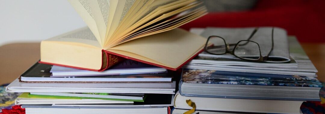 Bücherstapel mit einer Lesebrille oben aufliegend